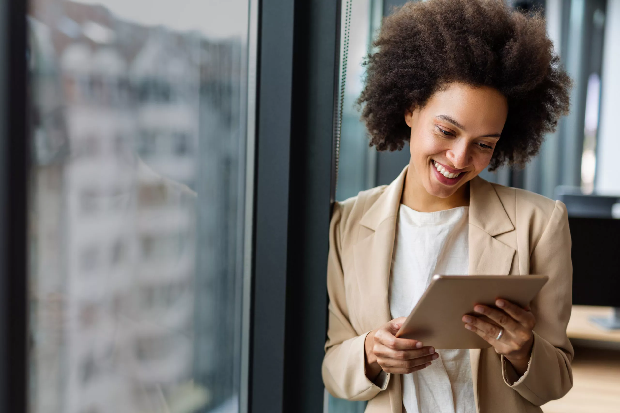 Femme souriante utilisant une tablette près d’une fenêtre
